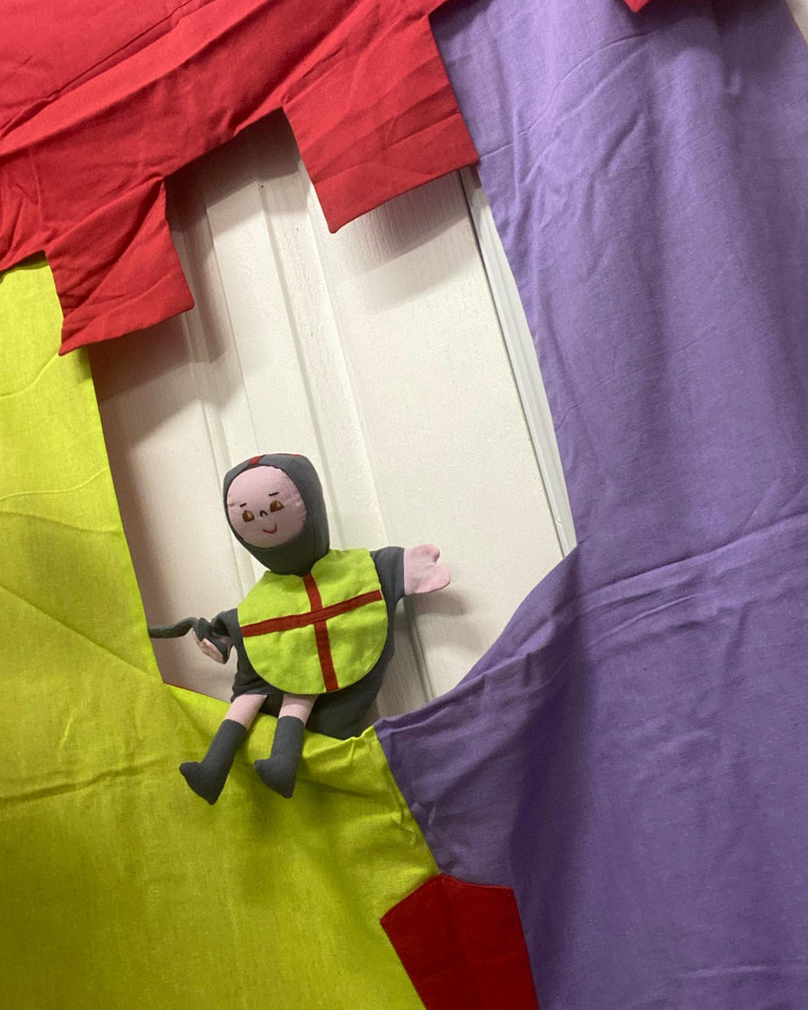 A colorful puppet showboard theatre with a kingdom theme, featuring red, blue, and yellow panels with a white castle-like cutout.