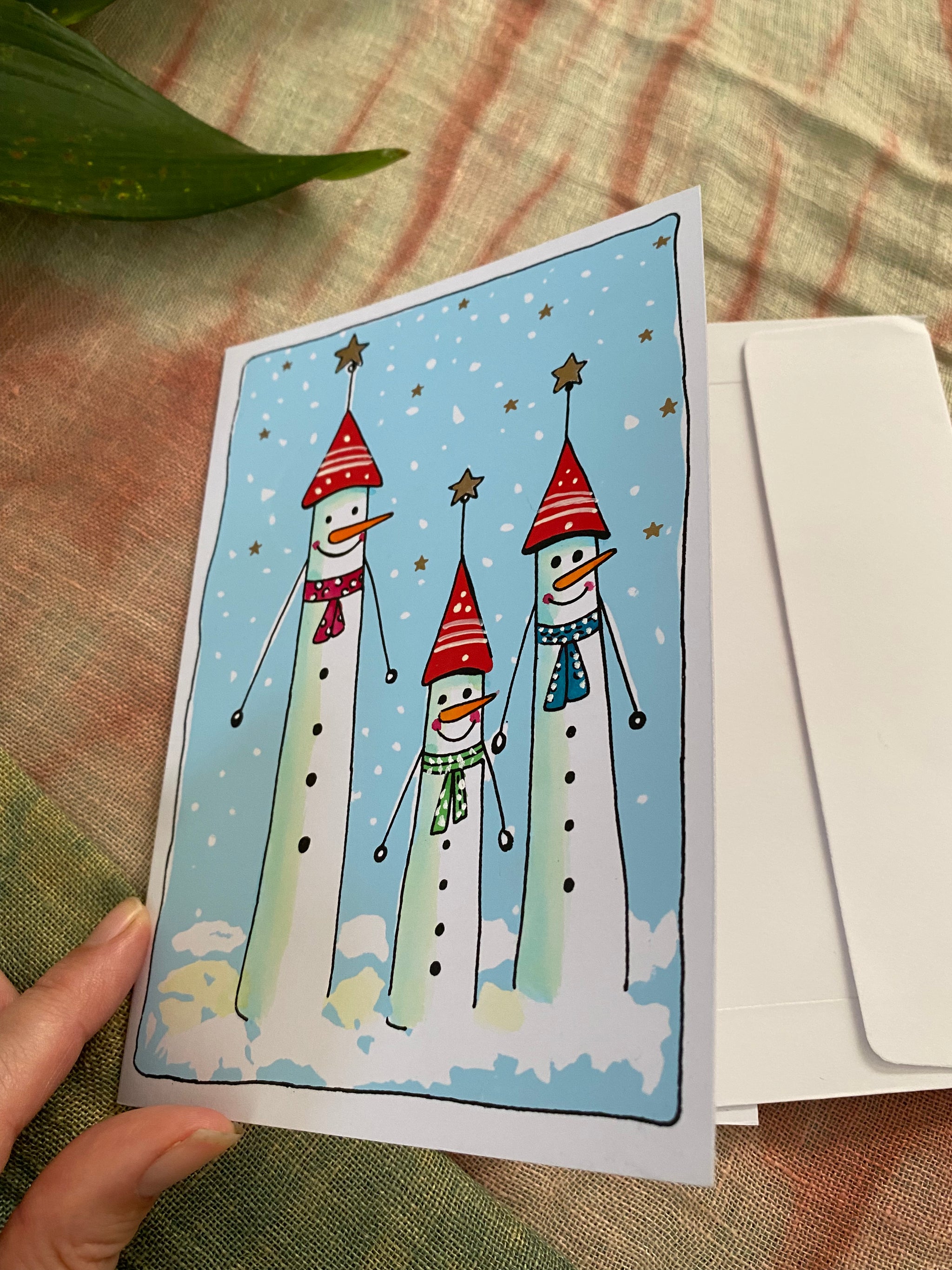 Card with snowmen design held by a hand on a textured surface