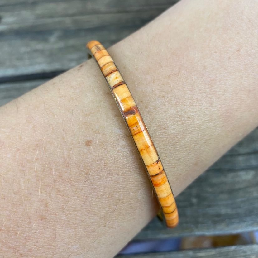 detail of orange resin and metal bangle on modals arm