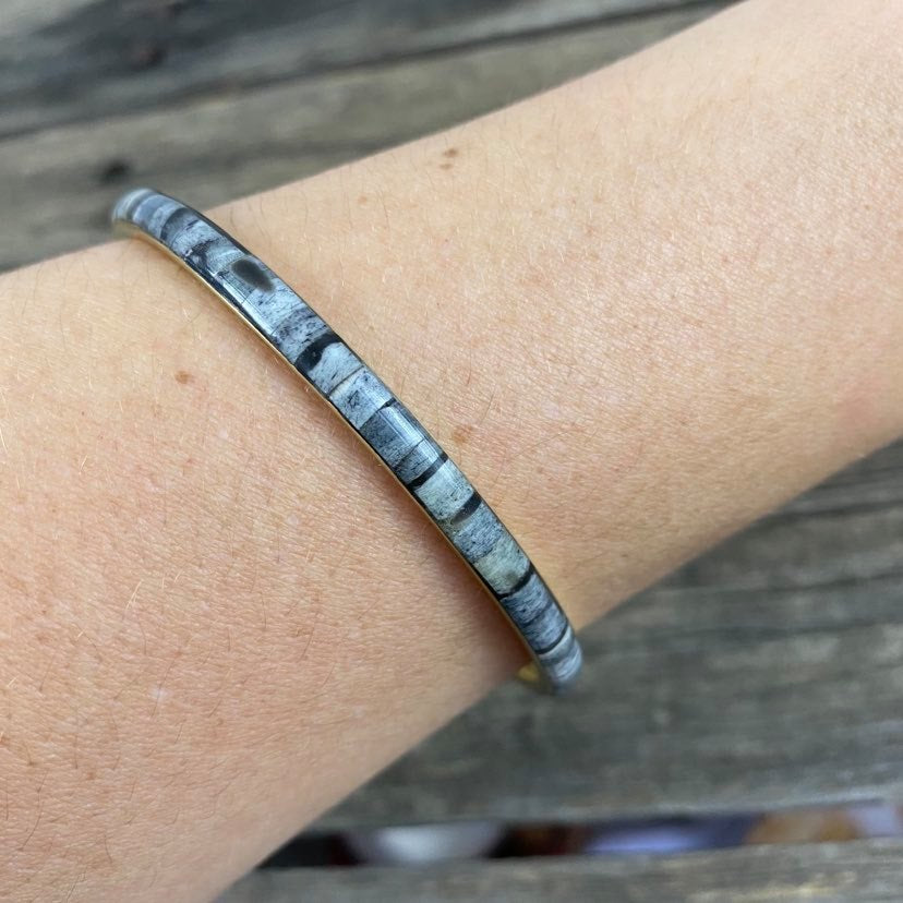 detail of grey resin and metal bangle on modals arm