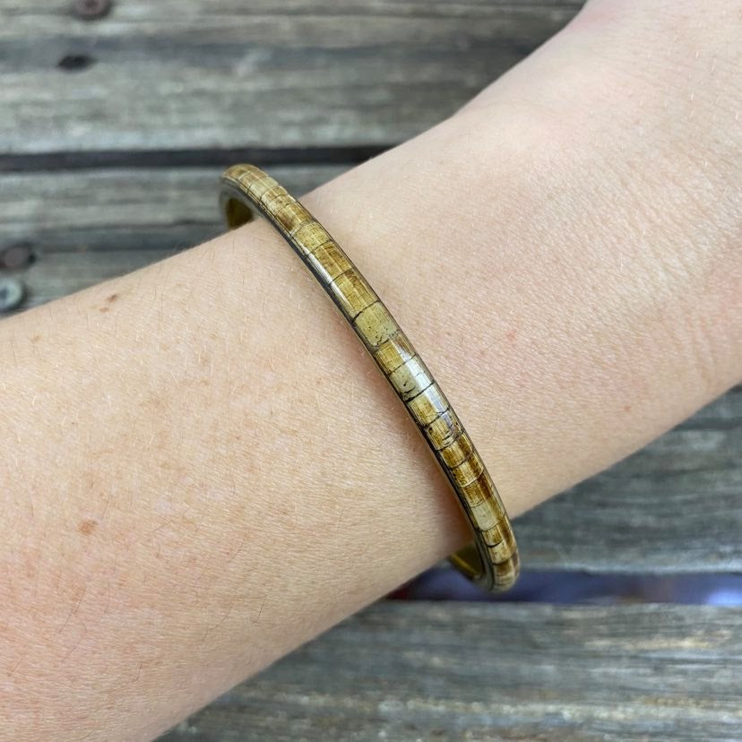 detail of brown resin and metal bangle on modals arm