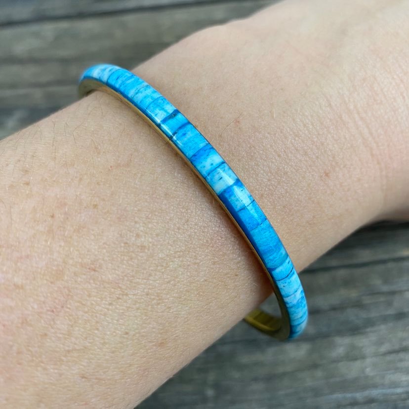 detail of aqua resin and metal bangle on modals arm