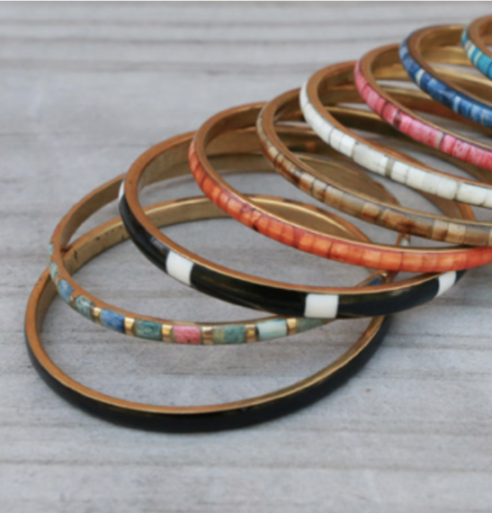 stack of our metal and resin bangles in different colours. in order from top to bottom, gold, aqua, blue, pink, white, brown, orange, black and white, multi-coloured, black   