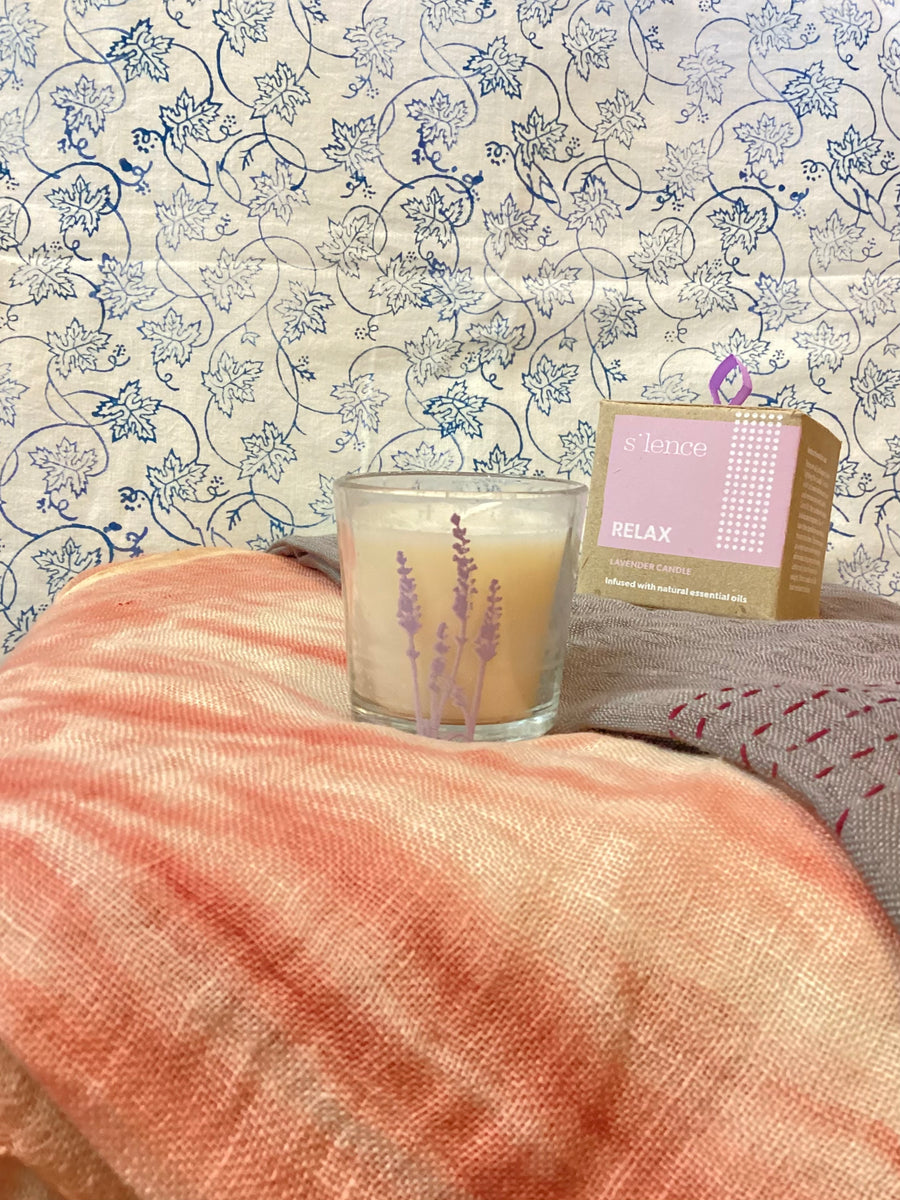 Candle and packaging on a textured surface with floral patterned fabric in the background