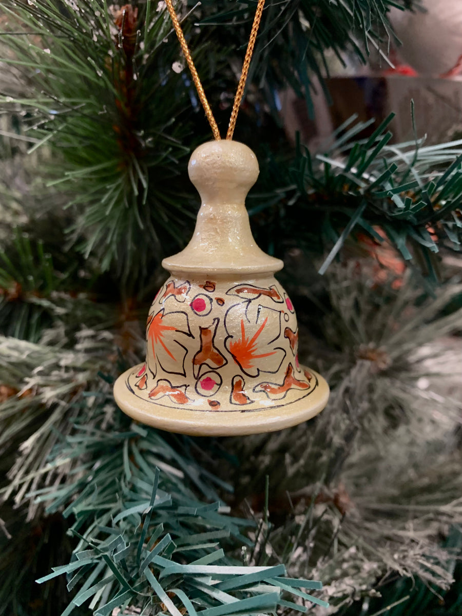 Two vintage style hand-painted wooded bell ornaments hanging from gold-colored cord against a textured off-white wall.