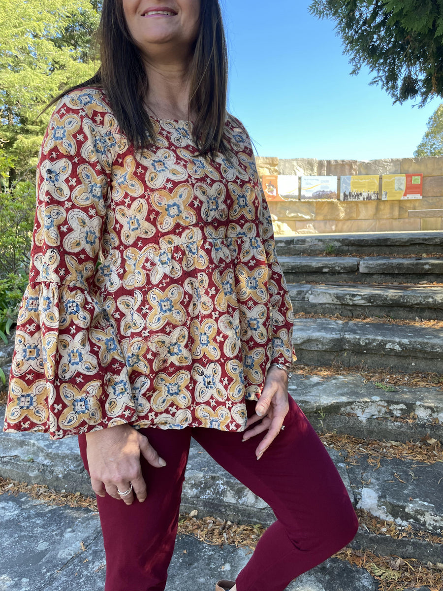 Fair trade ethical bell sleeve top with square neck, a maroon coloured patterned design with traditional Indian Tanjore Art - large flowers of yellow and creme decorate the fabric 