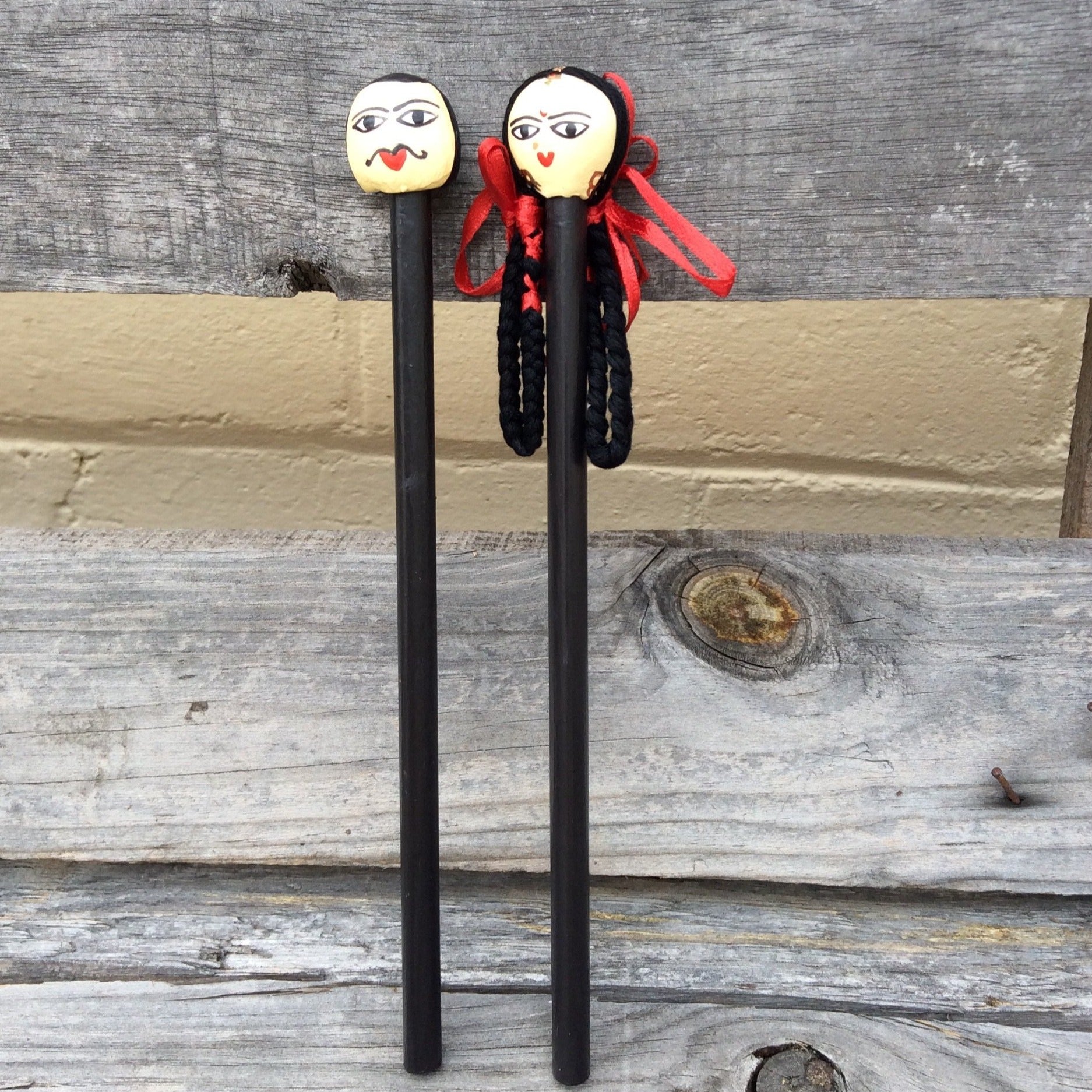Black pencil with girl and or boy head, girl has long black hair with red ribbons