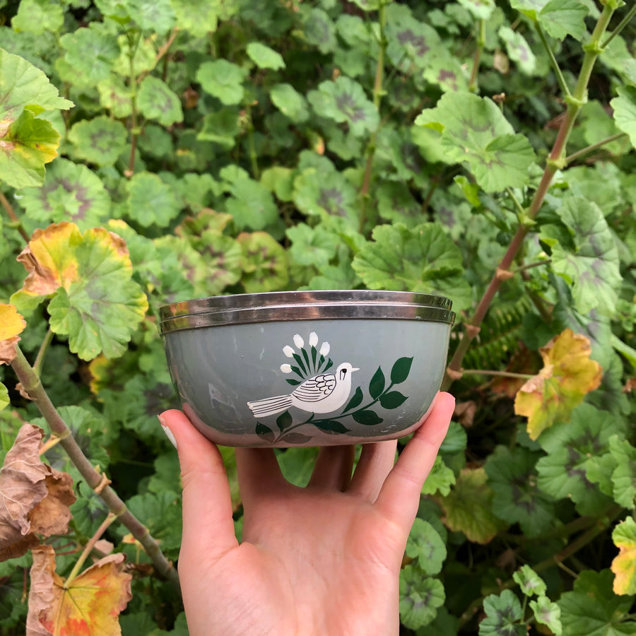 Photo of grey cup with hand painted white birds on green branch around the circumference of the exterior of the cup   