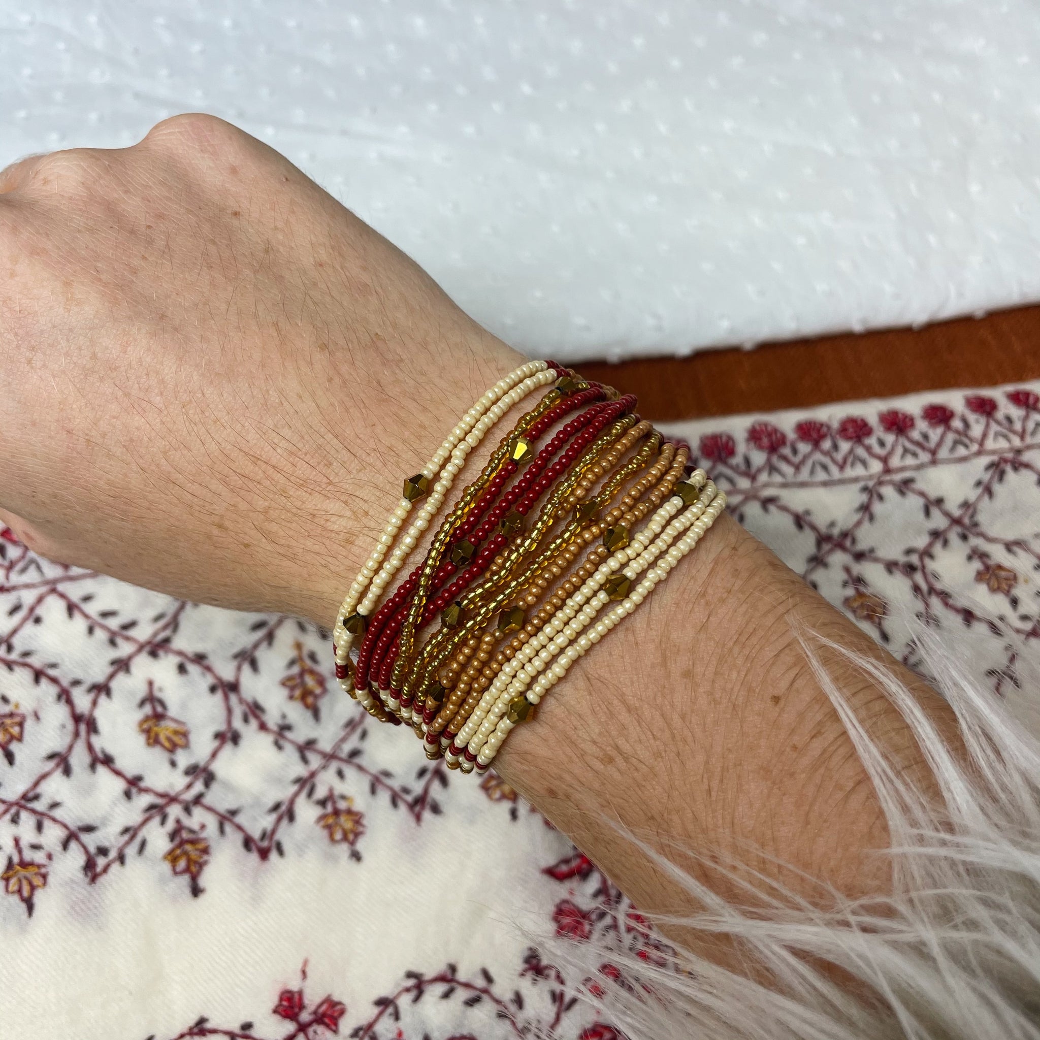 Multiple layered beaded bracelet with cream, copper, gold and maroon beads.